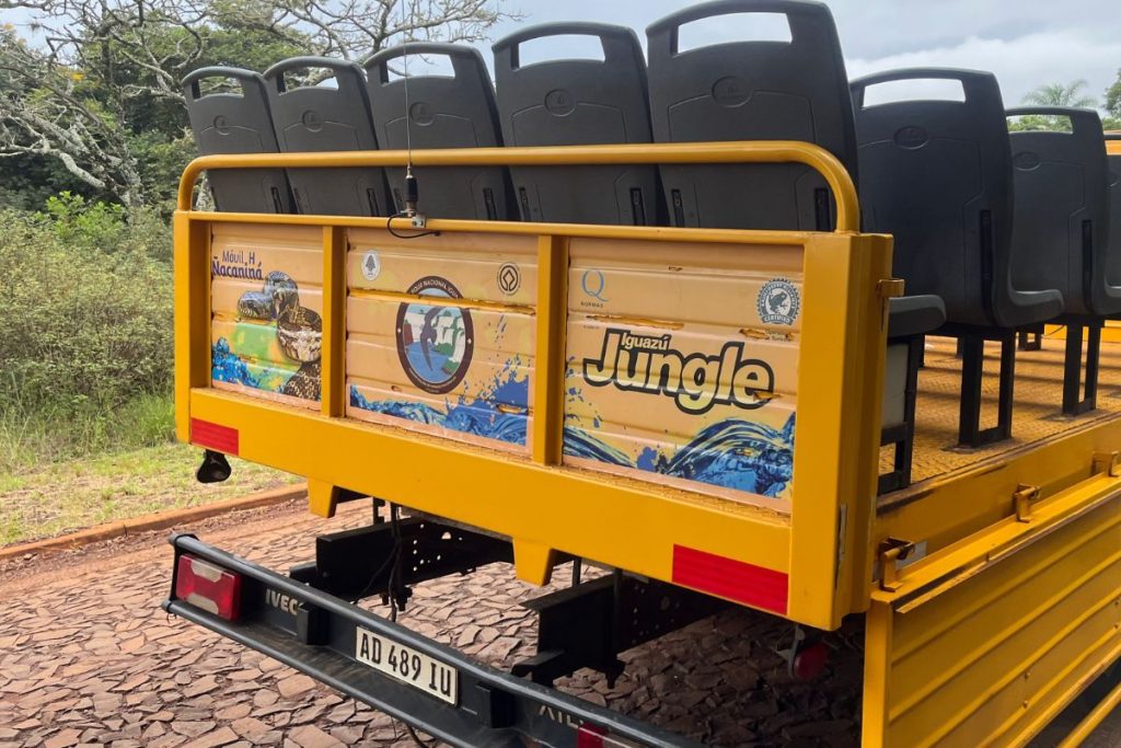 Yellow open-sided 4x4 truck with rows of black seats and an Iguazú Jungle logo on the back panel