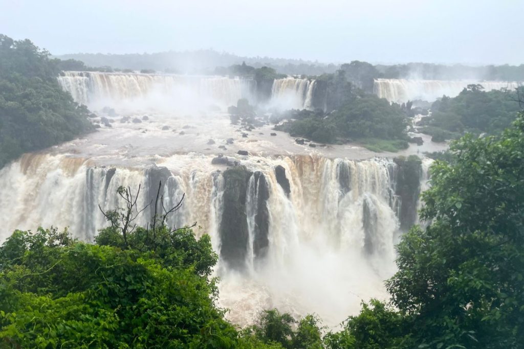 Iguazu Falls from the Brazilian side, brown water pouring over wide cliffs in a misty rainforest