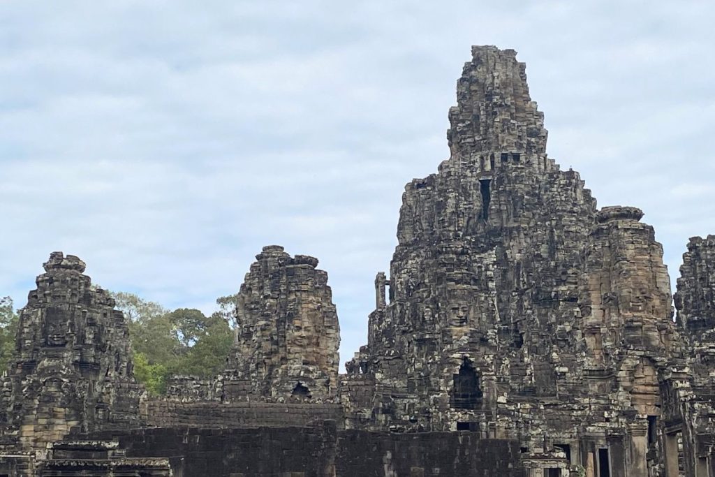 Weathered stone towers of Bayon temple rising against a cloud
