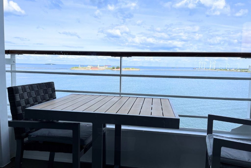 A view of a balcony of a cruise ship cabin, with a small island with a few small buildings in the background