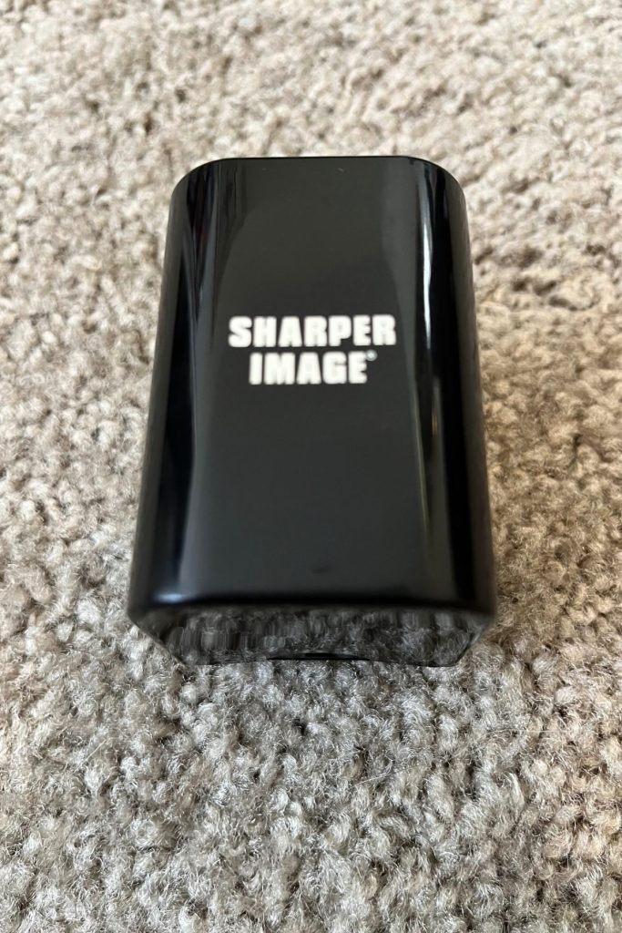A shiny, rectangular, black plastic case with the words Sharper Image embossed in white in the middle.