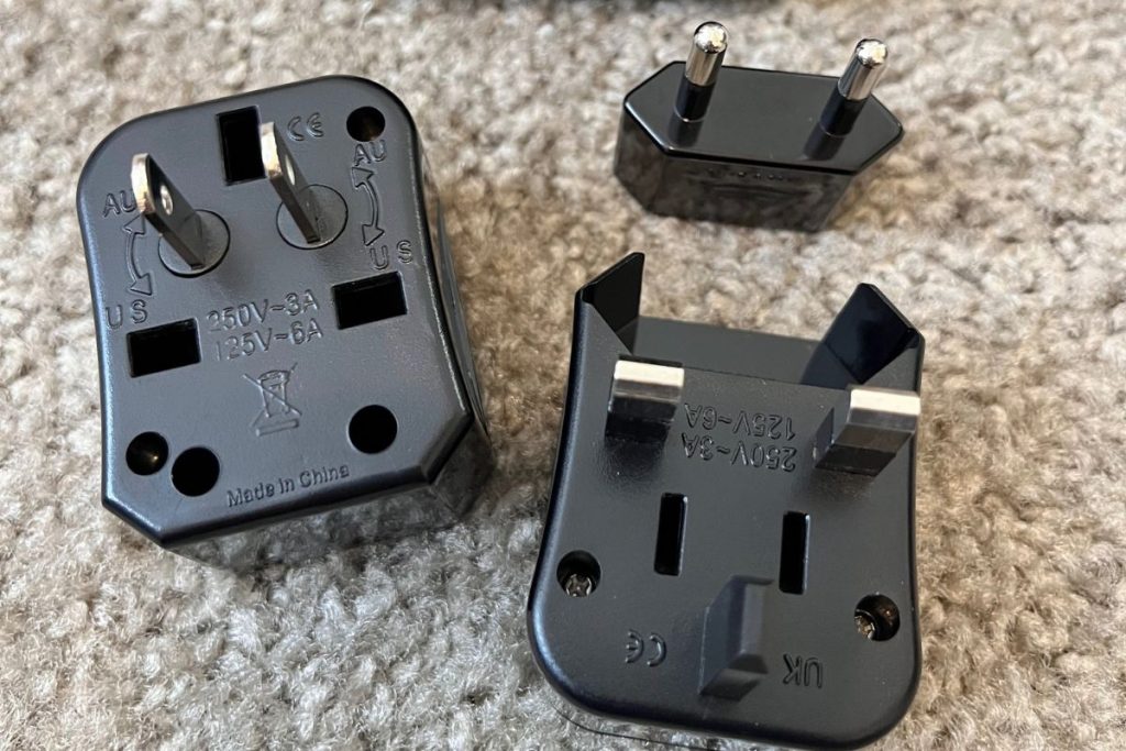 A set of nesting travel adapter plugs, separated into three pieces. Each piece is black plastic, with silver plugs of different sizes extending from each piece. There are also open slots and various words and numbers, such as Made in China and 250V-3A embossed on each piece.