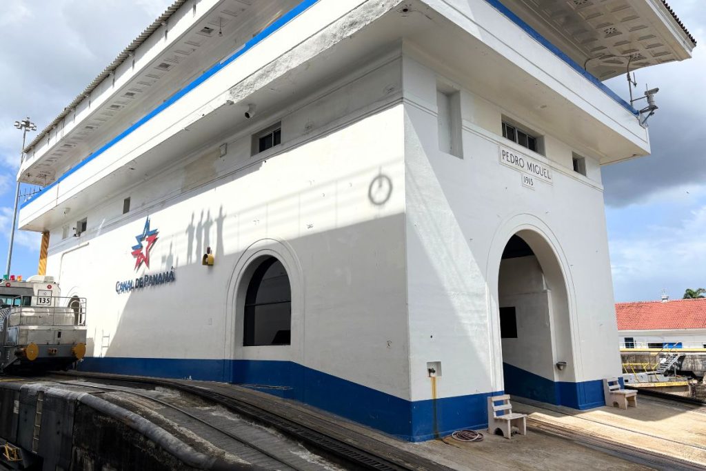 White control house with blue trim and arched openings, a Pedro Miguel 1913 sign, and a Canal de Panamá logo on the wall