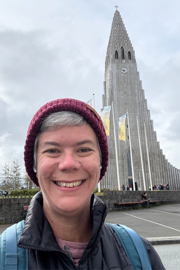 Smiling woman in a burgundy knit hat in front of the Hallgrímskirkja tower