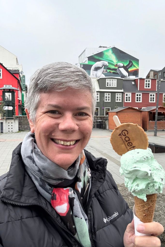 Woman holding a double scoop of mint chip gelato with a polar bear and puffin mural behind her