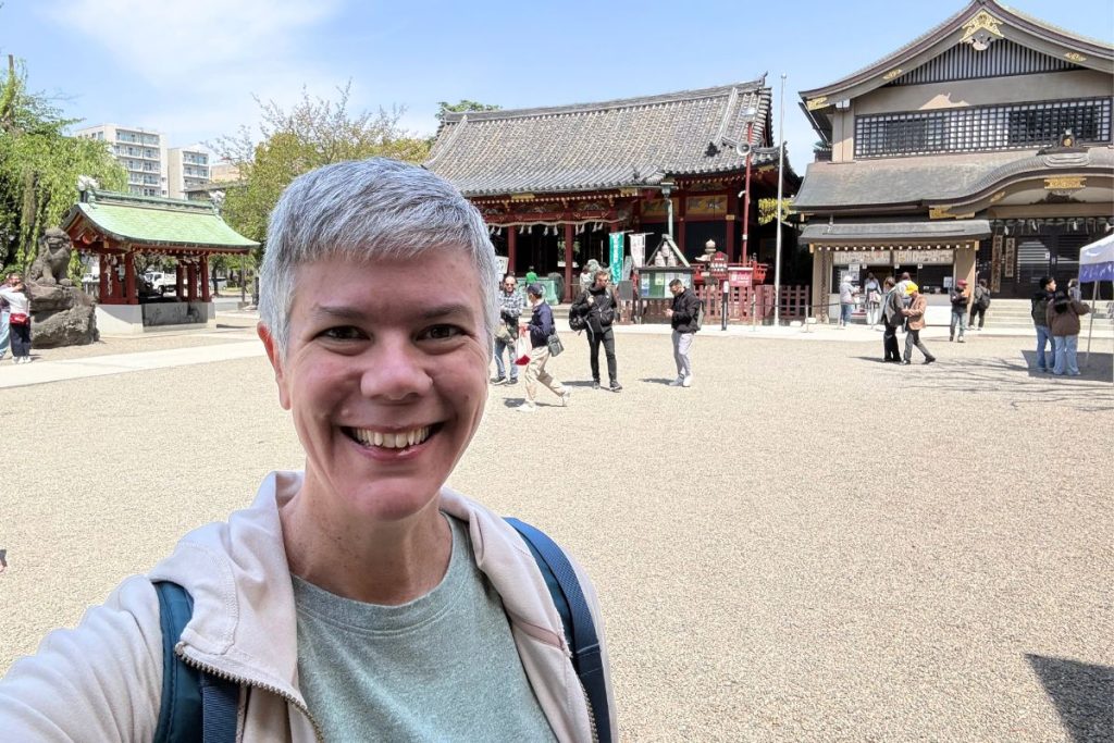 A woman smiling in front of the main hall at Asakusa Shrine
