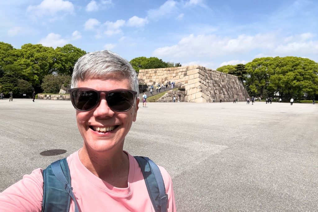 Woman smiling in front of the tenshudai, the stone foundation of the former Edo Castle keep