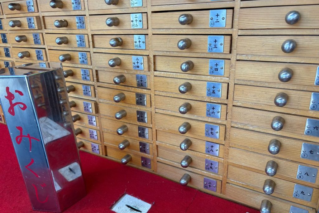 Wall of numbered omikuji drawers and collection box at Senso-ji