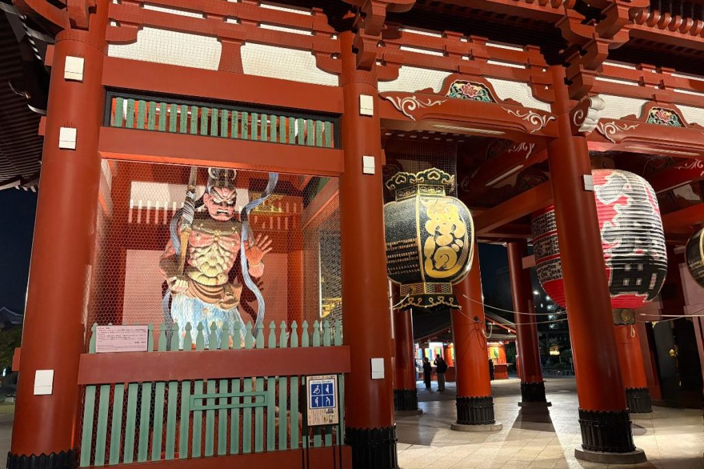 Illuminated guardian statue and lanterns inside Kaminari-mon Gate at night