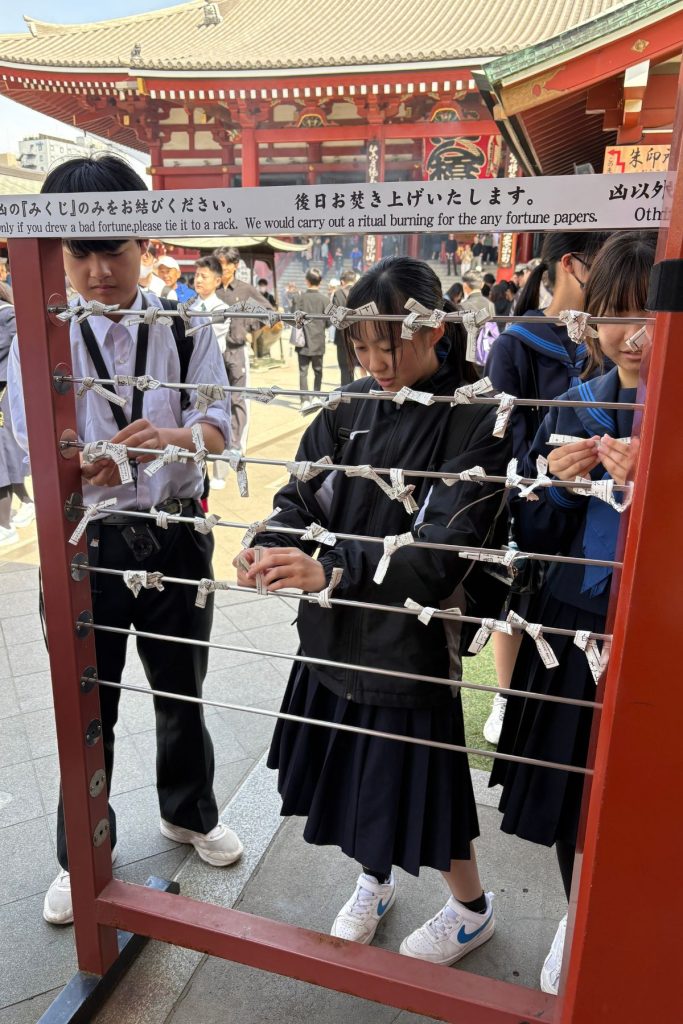 Visitors tying omikuji fortune papers to the rack at Senso-ji