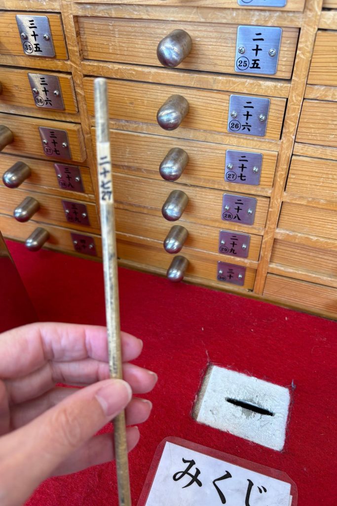 Hand holding a drawn numbered omikuji stick at Senso-ji