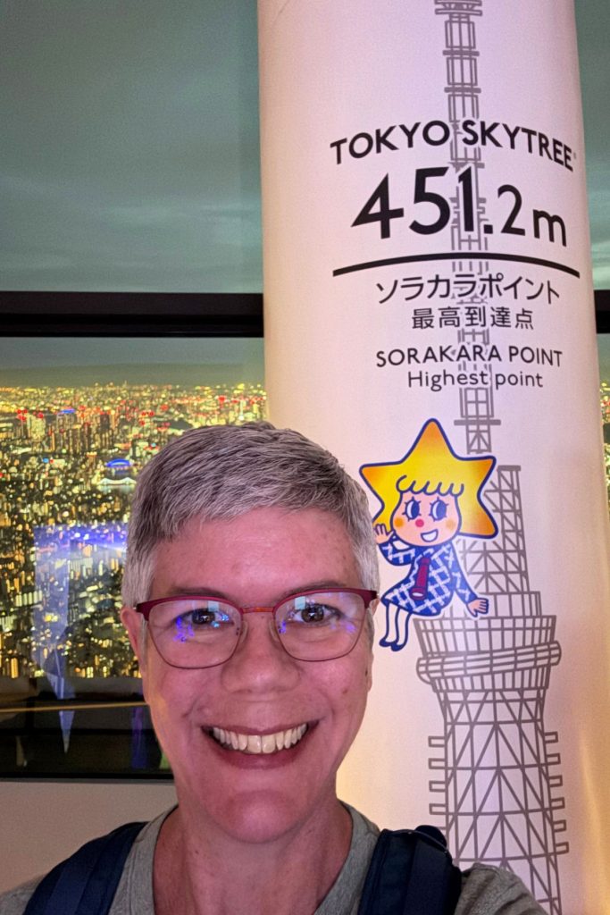 Woman smiling in front of the Sorakara Point sign, 451.2 meters, at Tokyo Skytree