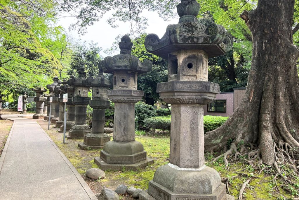 Row of weathered stone lanterns lining the path at Ueno Toshogu Shrine
