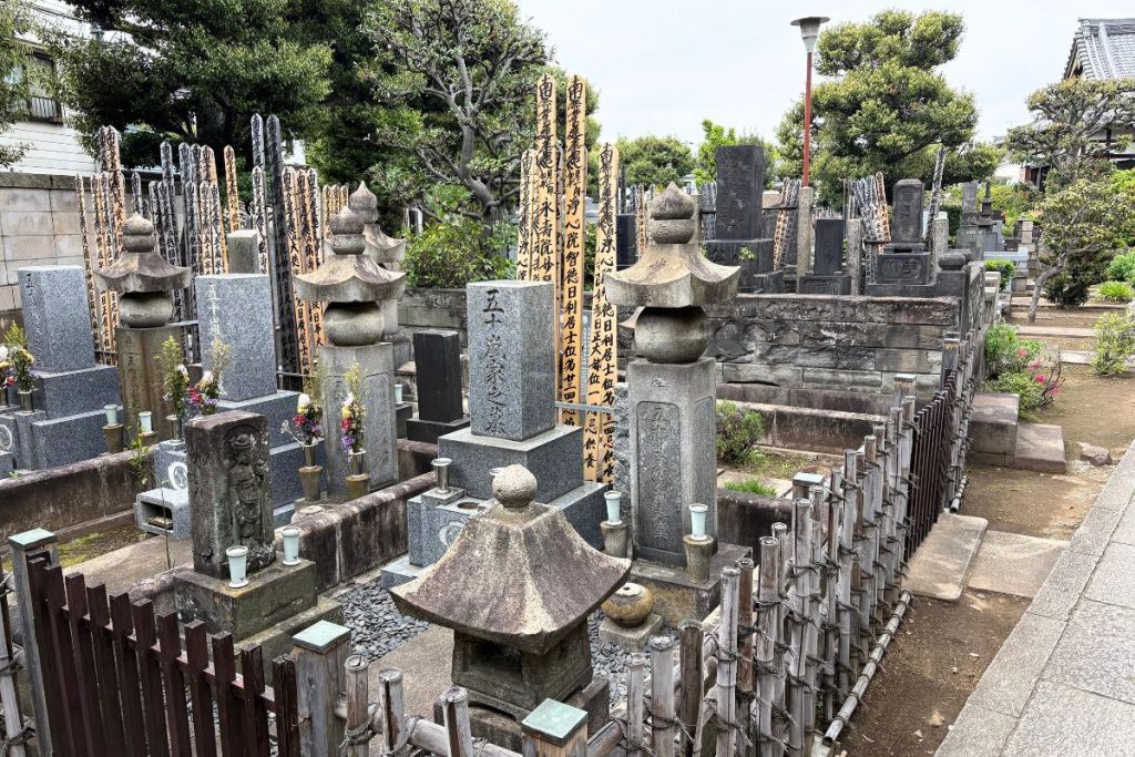 Rows of stone grave markers and lanterns in Yanaka cemetery