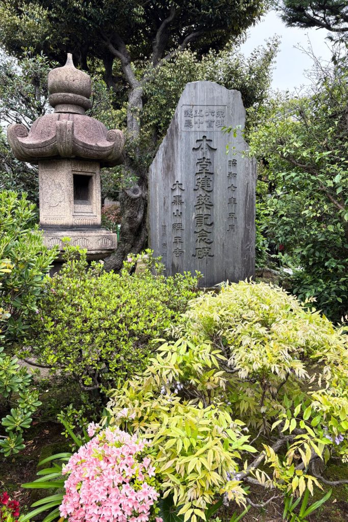 Stone lantern beside an inscribed memorial marker in a Yanaka temple garden