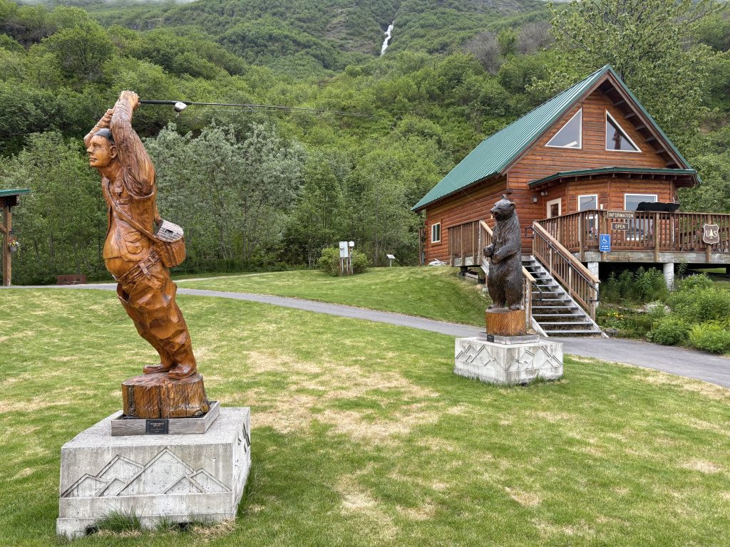 Carved wooden fisherman and bear statues outside a US Forest Service center in Valdez, Alaska