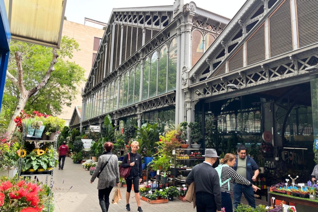 Flower market with vendors and blooms under vintage iron-and-glass structure in Barcelona