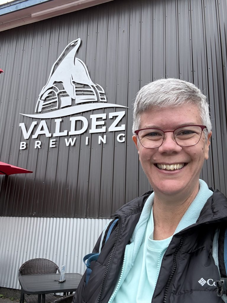 Selfie in front of the Valdez Brewing sign on the exterior of the building