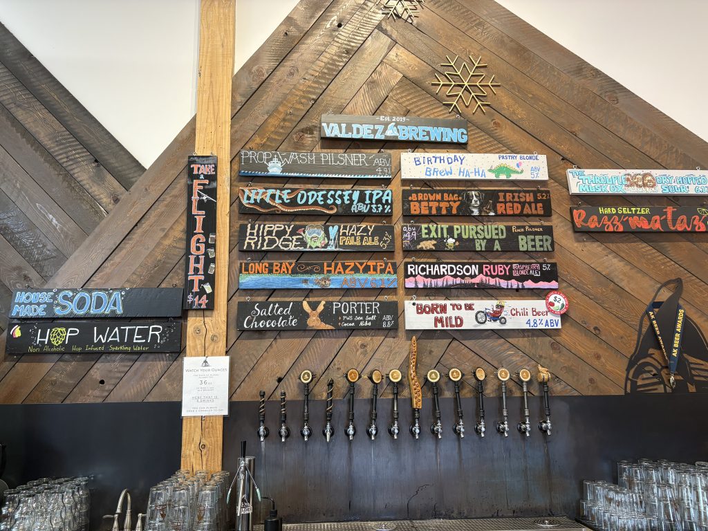 Hand-painted tap list at Valdez Brewing showing craft beer names and ABV percentages