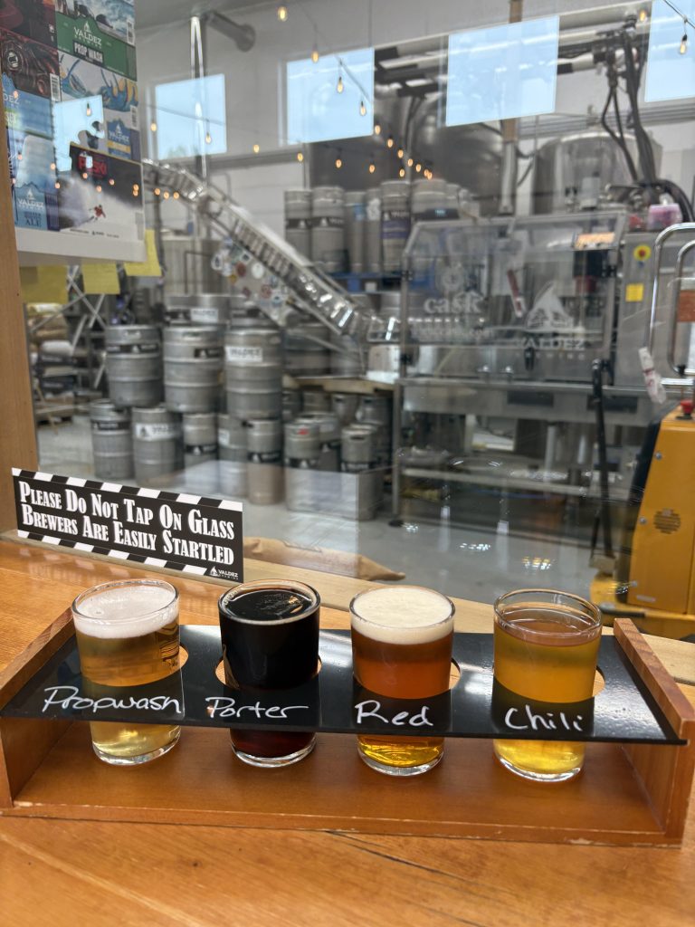 Flight of four beers labeled Propwash, Porter, Red, and Chili at Valdez Brewing