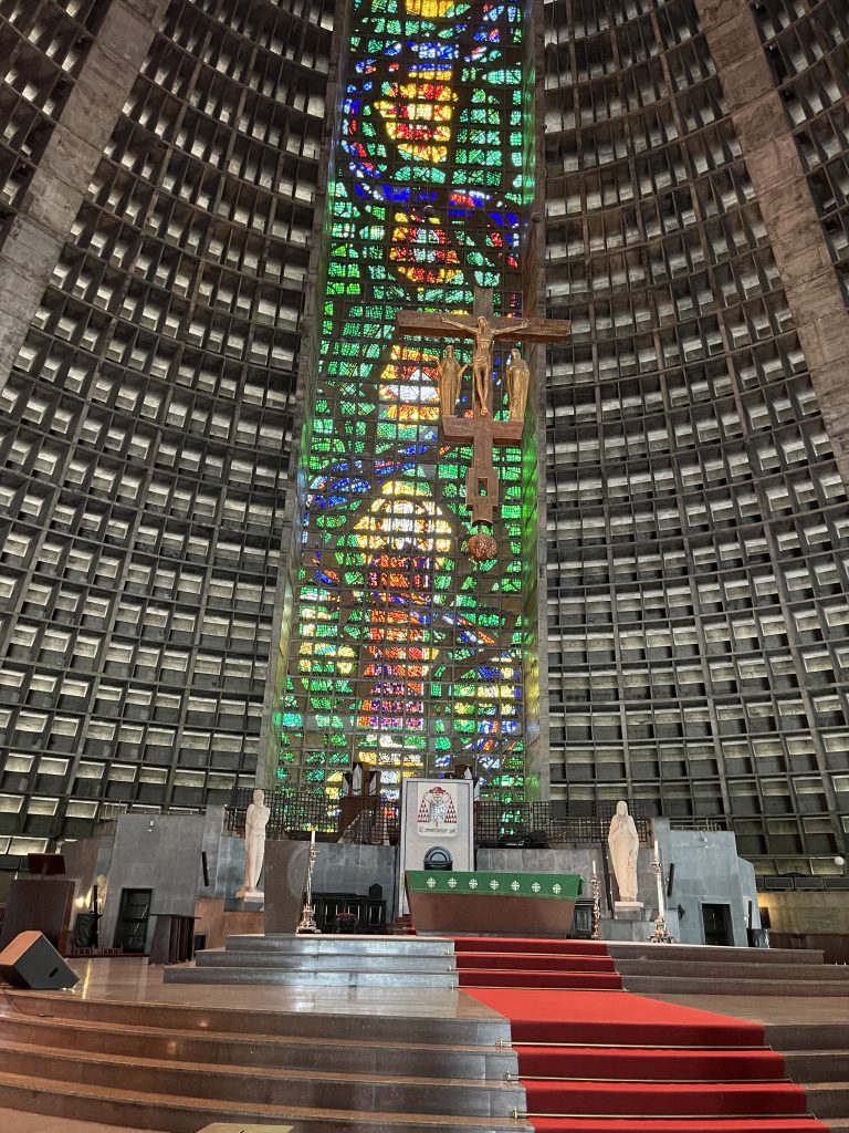 Interior of the Metropolitan Cathedral of Rio de Janeiro showing the altar, crucifix, and stained glass column