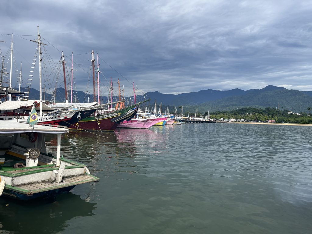 Colorful wooden boats moored in Paraty, Brazil's harbor with mountains in the background