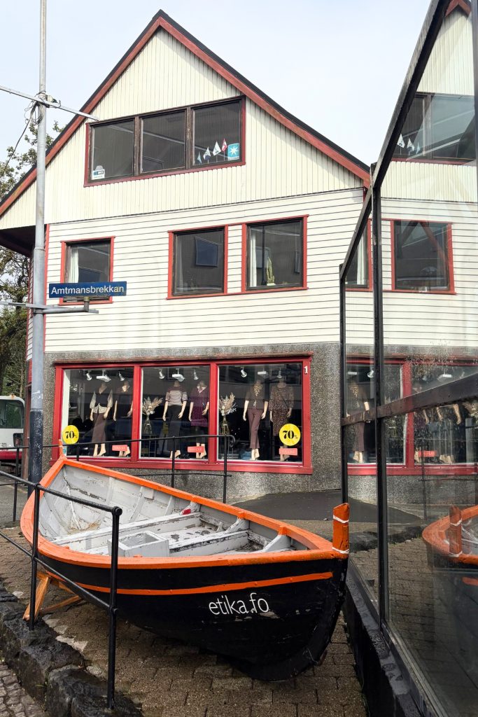 A weathered rowboat displayed outside a shop on a street corner in Tórshavn, Faroe Islands