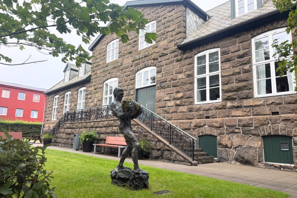 A stone building from 1894 with a bronze statue on the lawn, now Tórshavn's town hall