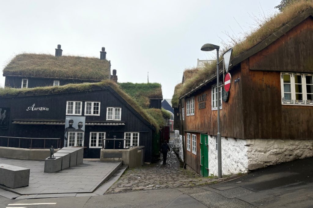 A narrow cobblestone alley lined with turf-roofed wooden buildings in Tórshavn's old town
