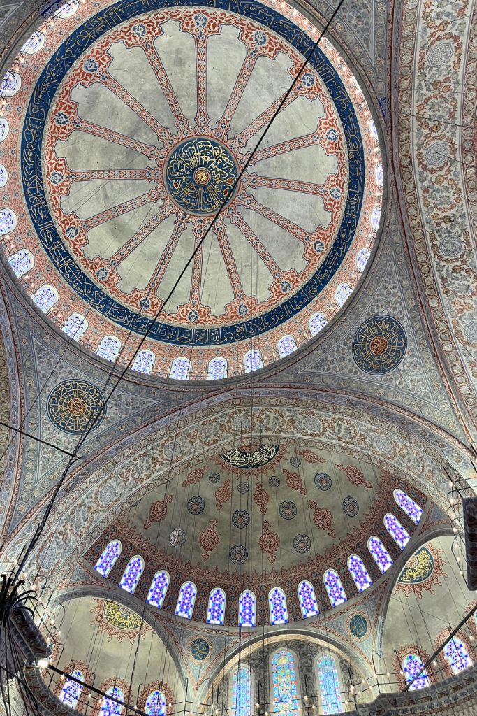 Close-up of a Blue Mosque dome ceiling featuring a circular medallion of Arabic calligraphy surrounded by radiating geometric and floral tilework.