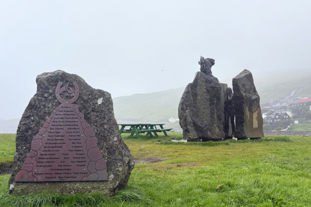 A bronze and stone statue depicting a Faroese folk legend near Sandavágur church