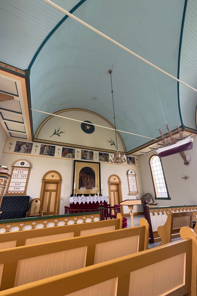 The painted altar and pale blue vaulted ceiling inside Sandavágur church