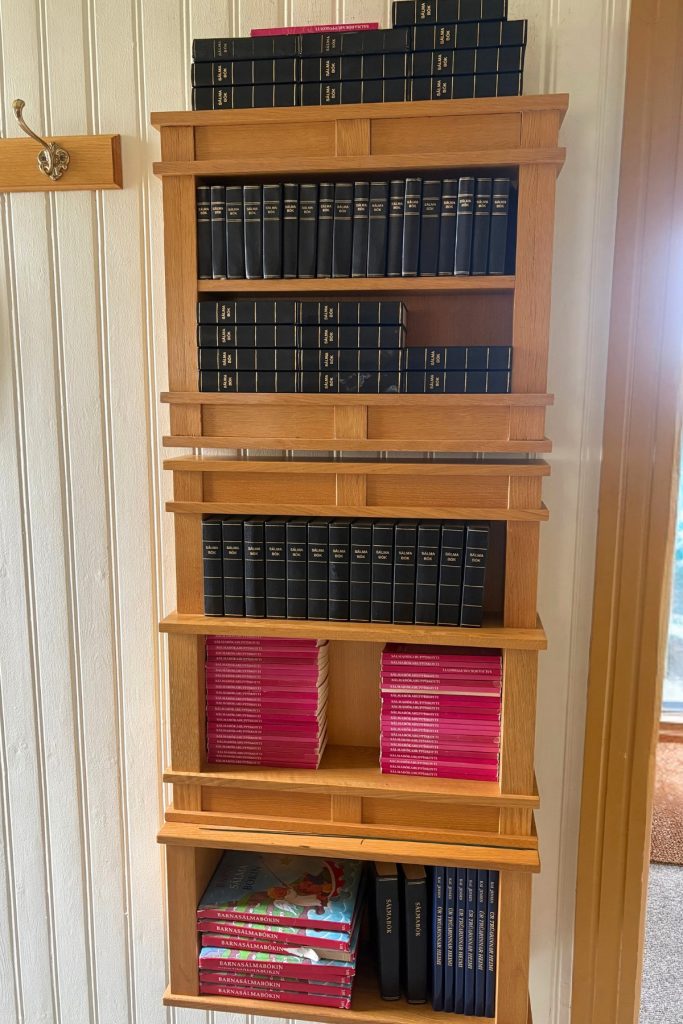A wooden shelf holding hymnals near the entrance of Sandavágur church