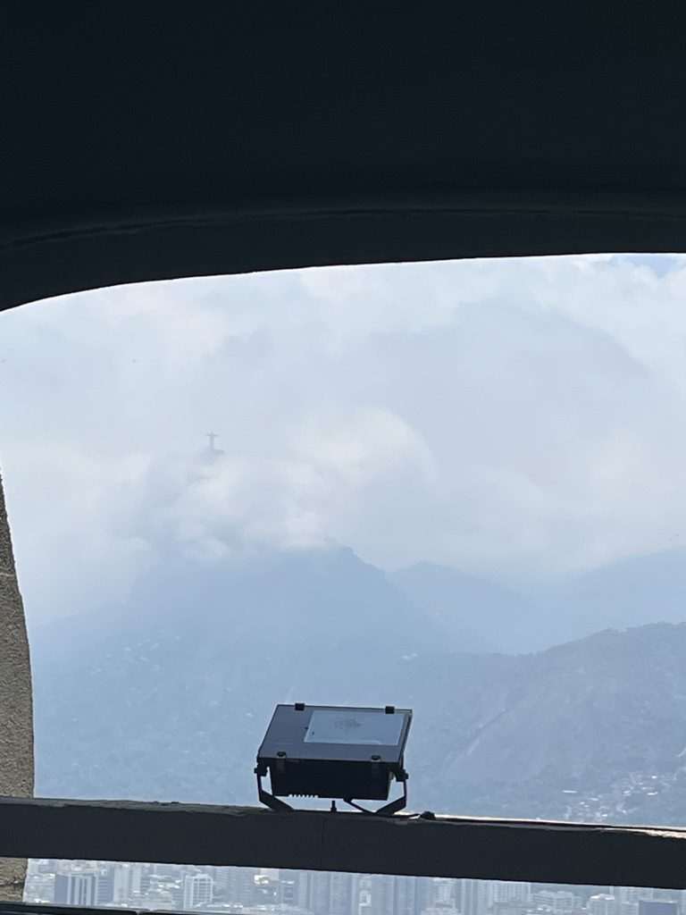 Hazy silhouette of Christ the Redeemer statue seen through clouds from Sugarloaf Mountain in Rio de Janeiro