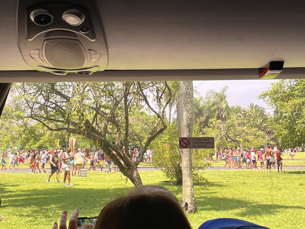 Carnival street party crowd gathered in a park, seen through a tour bus window in Rio de Janeiro