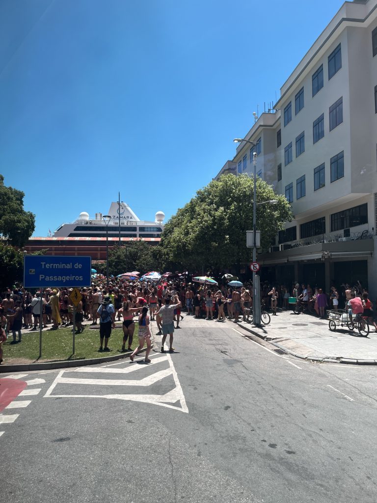 Azamara cruise ship visible above a Carnival crowd near the Terminal de Passageiros sign in Rio de Janeiro