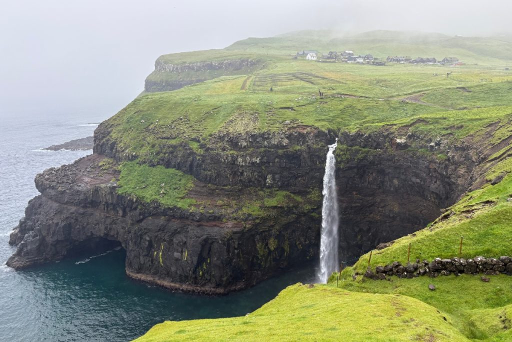 Múlafossur waterfall falling from a cliff into the sea near the village of Gásadalur, Faroe Islands