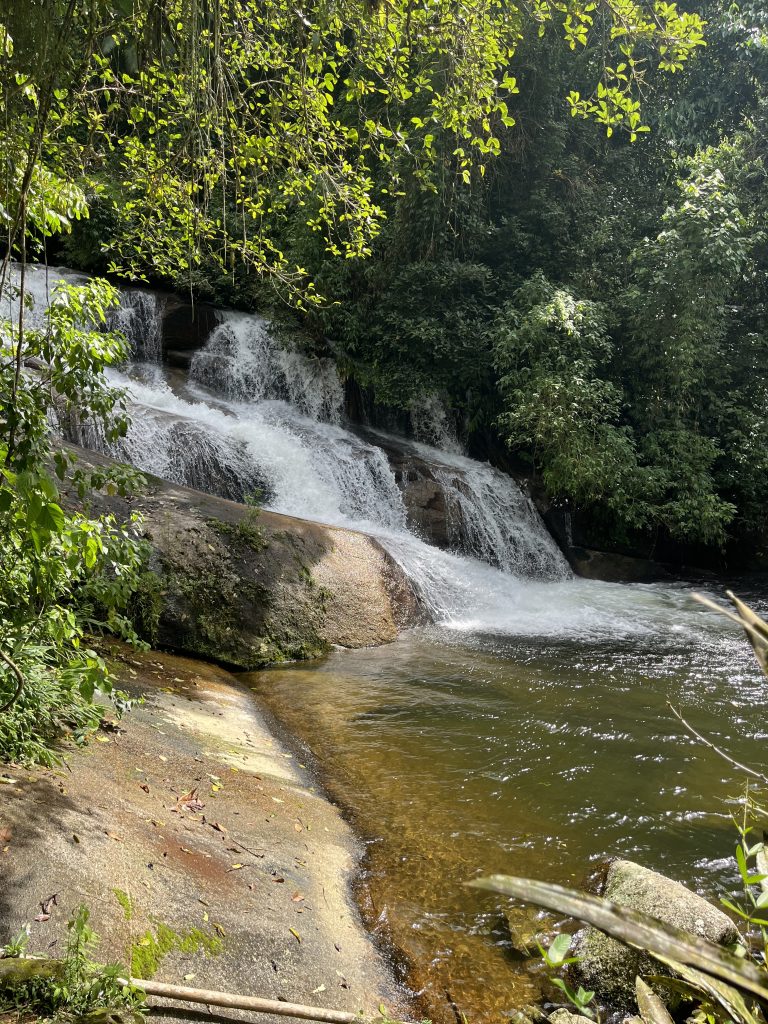 Pedra Branca waterfall dropping over smooth rock into a green pool in Paraty, Brazil