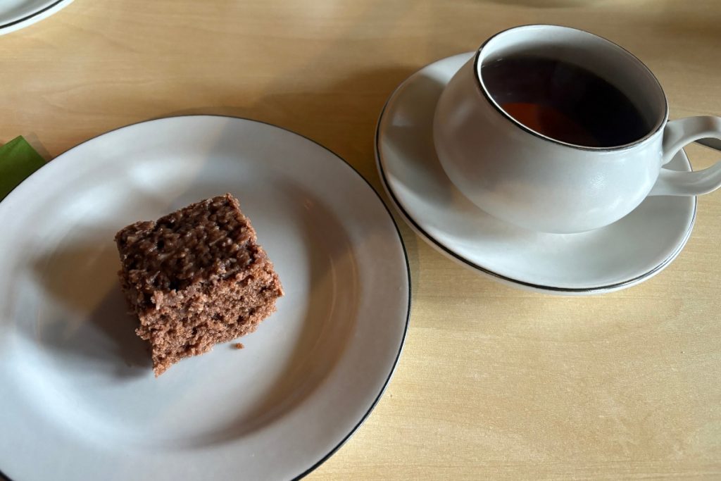 A square of dark cake and a cup of tea on white china at Pakkhúsið café