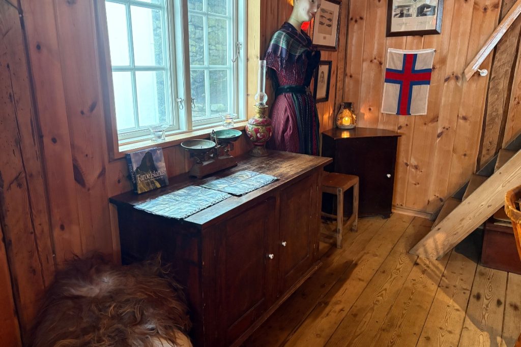 A mannequin in traditional Faroese dress standing in a wood-paneled room at Pakkhúsið
