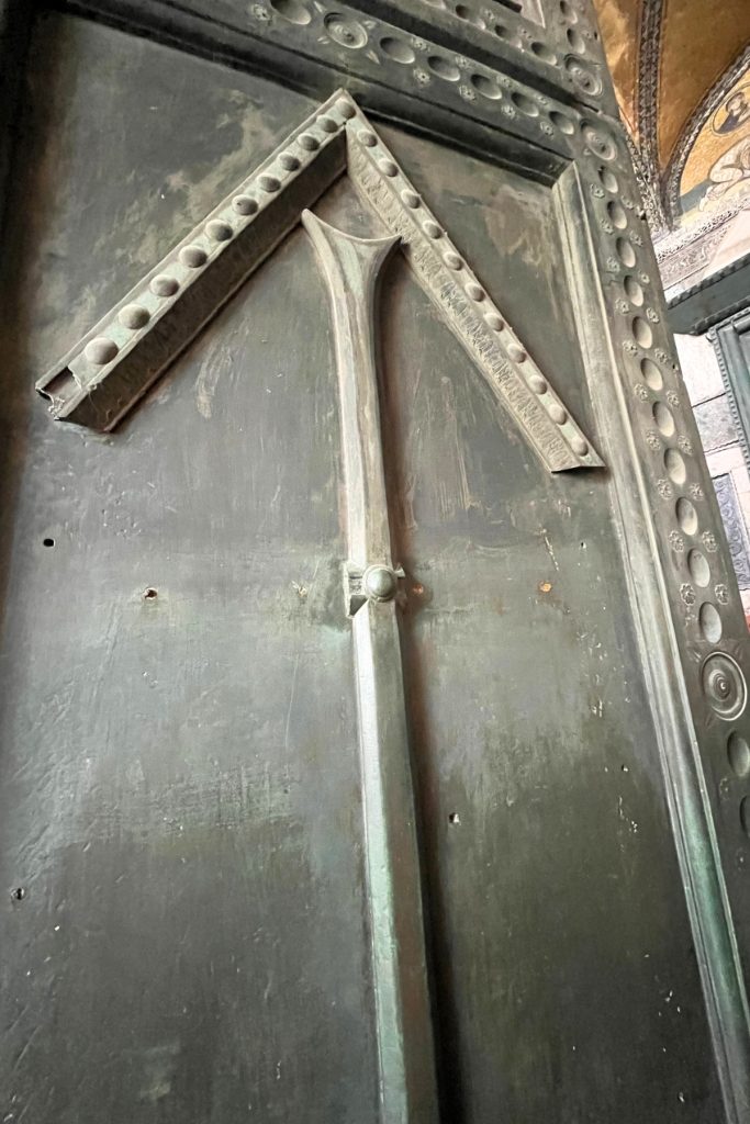 Close-up of a bronze door at Hagia Sophia showing an arrow-shaped design at the top, with visible holes where crossbars were originally mounted lower.