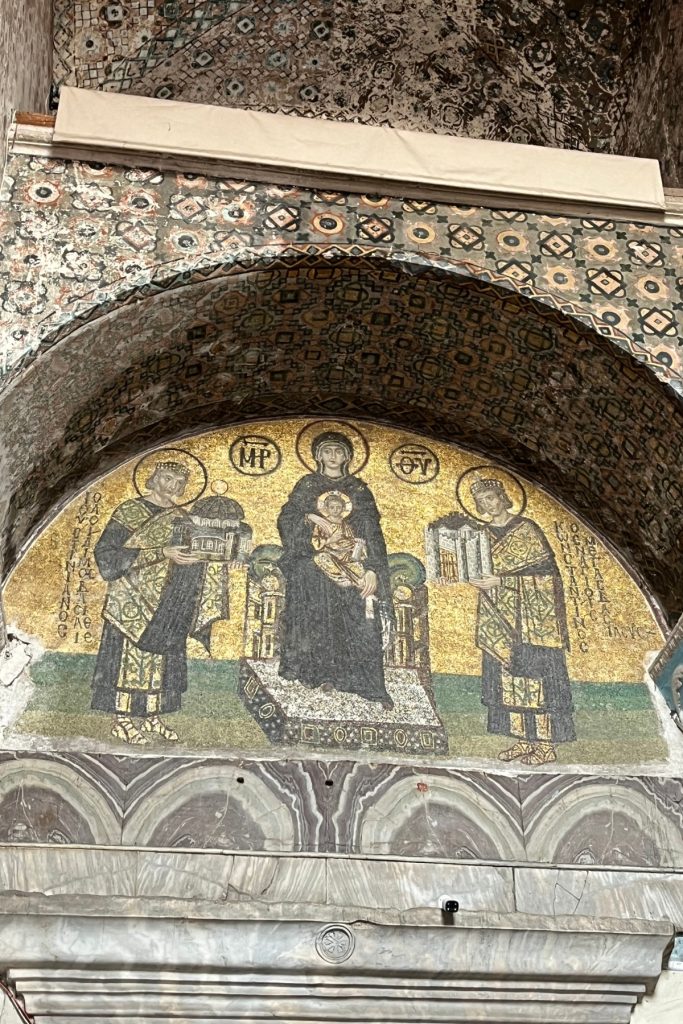 Byzantine gold mosaic above a doorway in Hagia Sophia depicting the Virgin Mary and Christ Child flanked by Emperor Constantine and Emperor Justinian, each holding a model building.