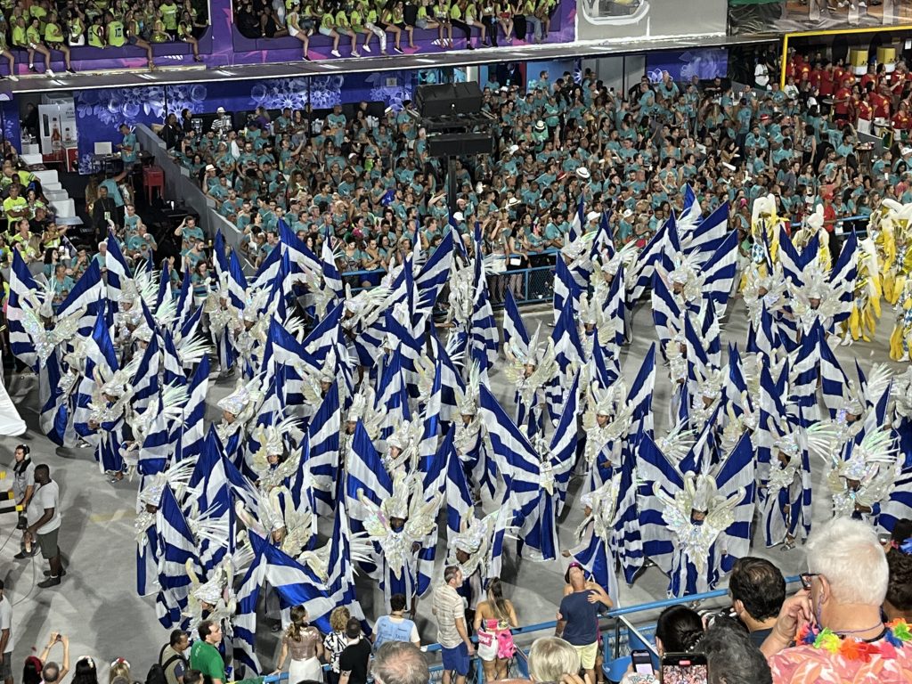 Aerial view of dancers in blue and white flag-bearer formation at the Sambódromo during Rio Carnival
