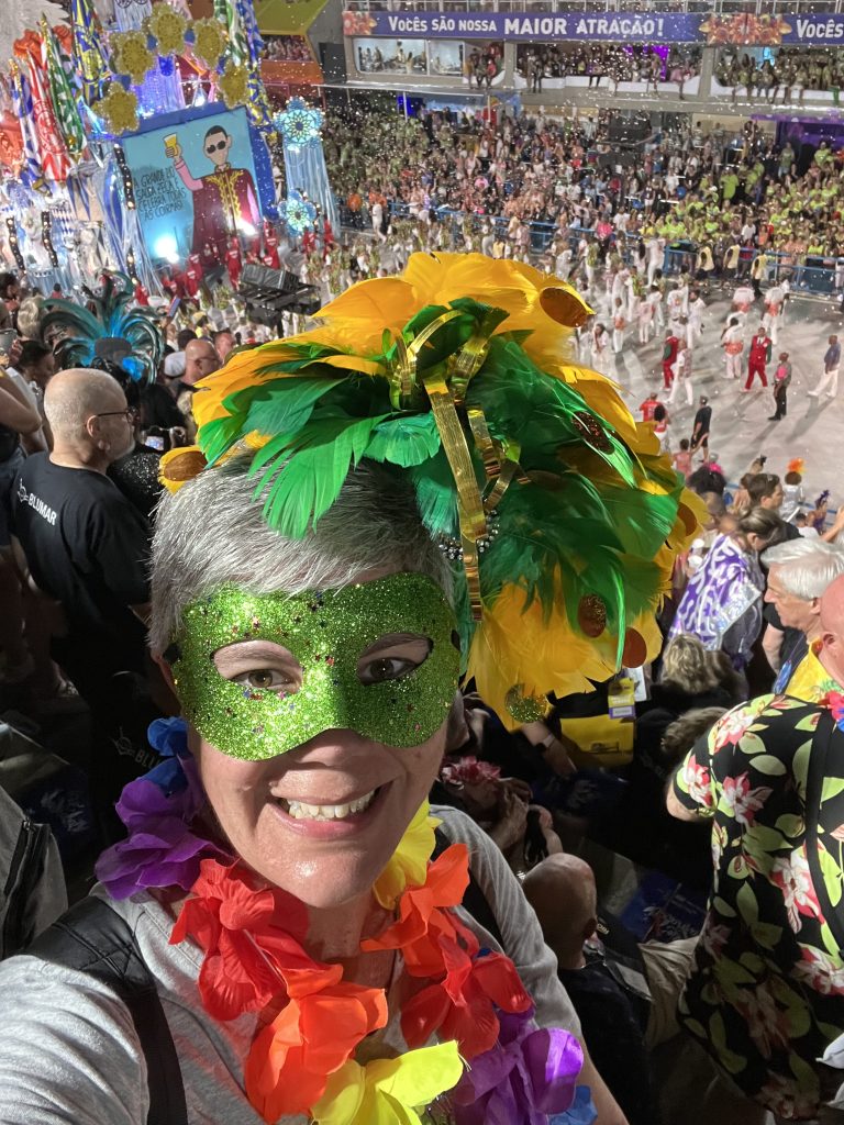 Selfie wearing a green glitter mask and yellow feather headpiece at the Sambódromo during Rio Carnival