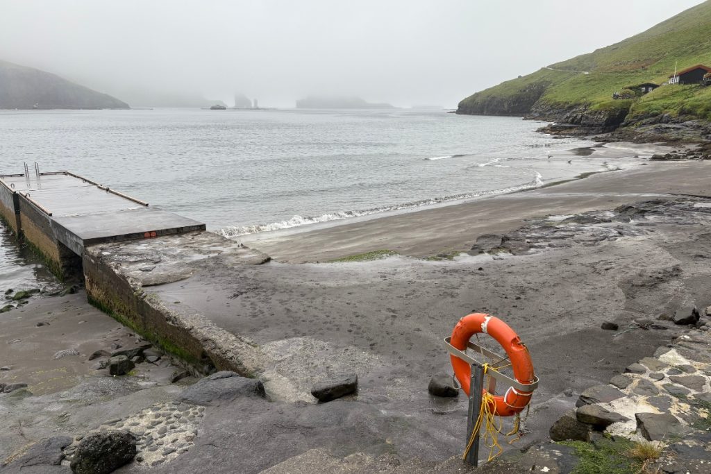A foggy view of the coastline and swimming platform near Bøur, with the Drangarnir sea stacks obscured in the distance