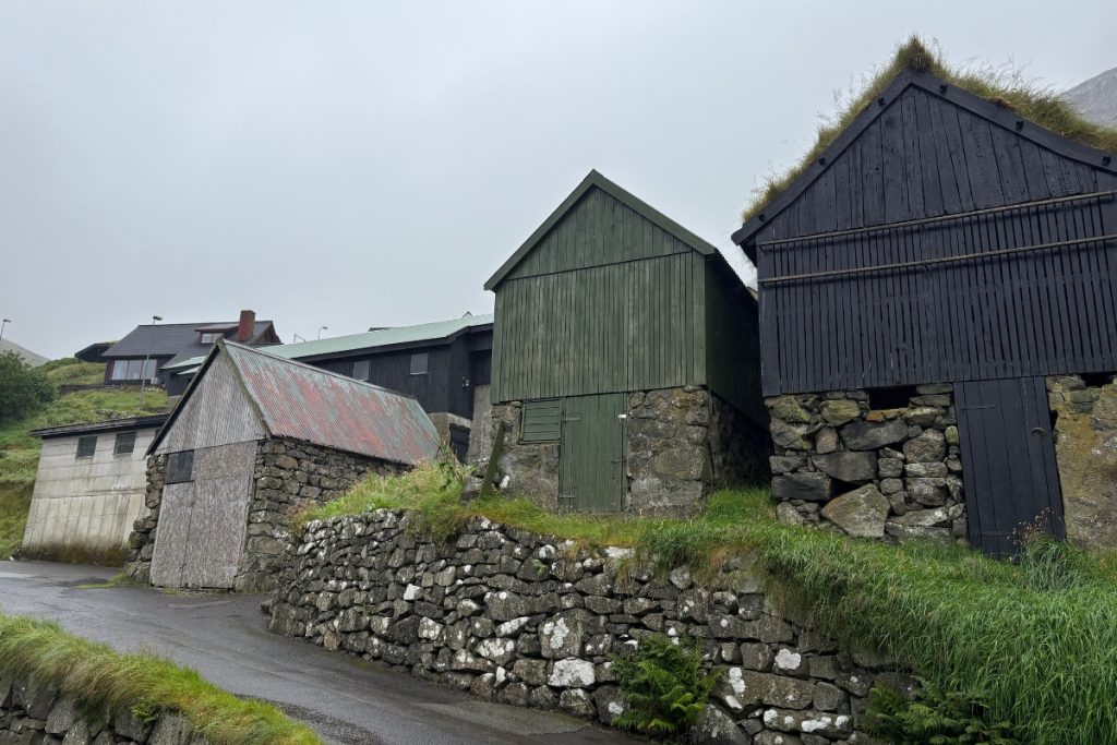 A cluster of stone and timber outbuildings along a lane in Bøur, Faroe Islands