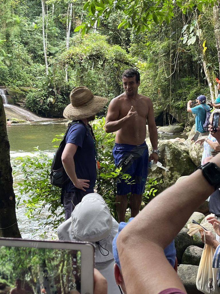 Local performer and onlookers at Tobogã waterfall near Paraty, Brazil