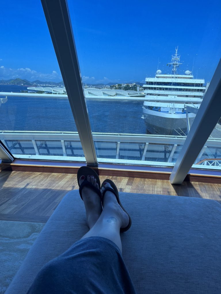 Feet up in flip-flops on a cruise ship balcony, overlooking another docked ship in Rio de Janeiro