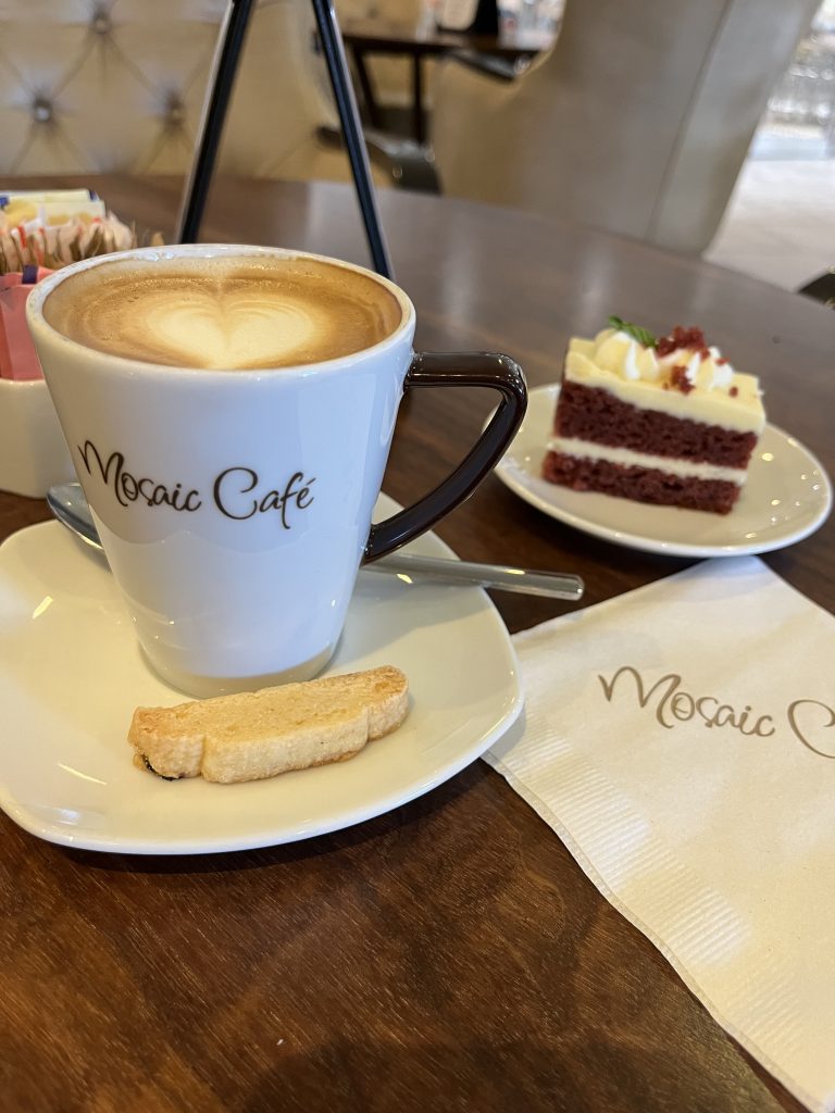 Cappuccino with heart-shaped latte art, a cookie, and red velvet cake at the Mosaic Café