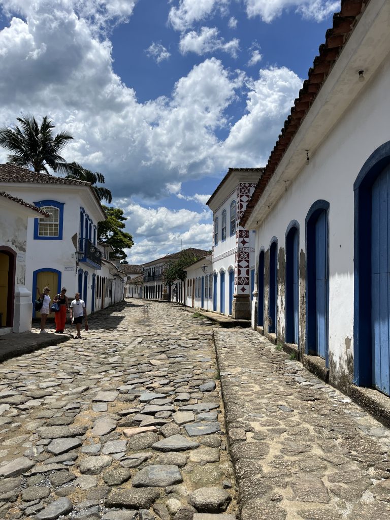 Tourists walking along a cobblestone street between colonial buildings in Paraty, Brazil